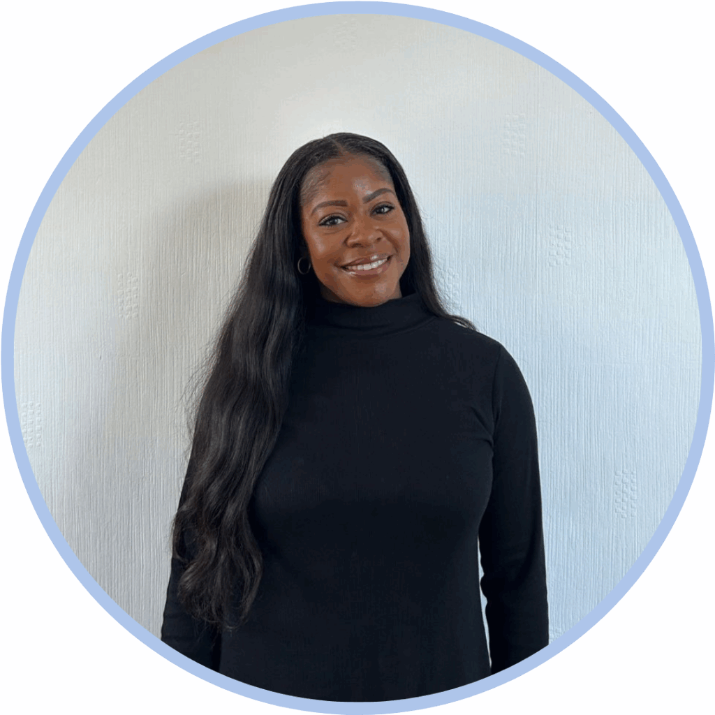 Black woman with black hair wearing a black top and smiling to camera