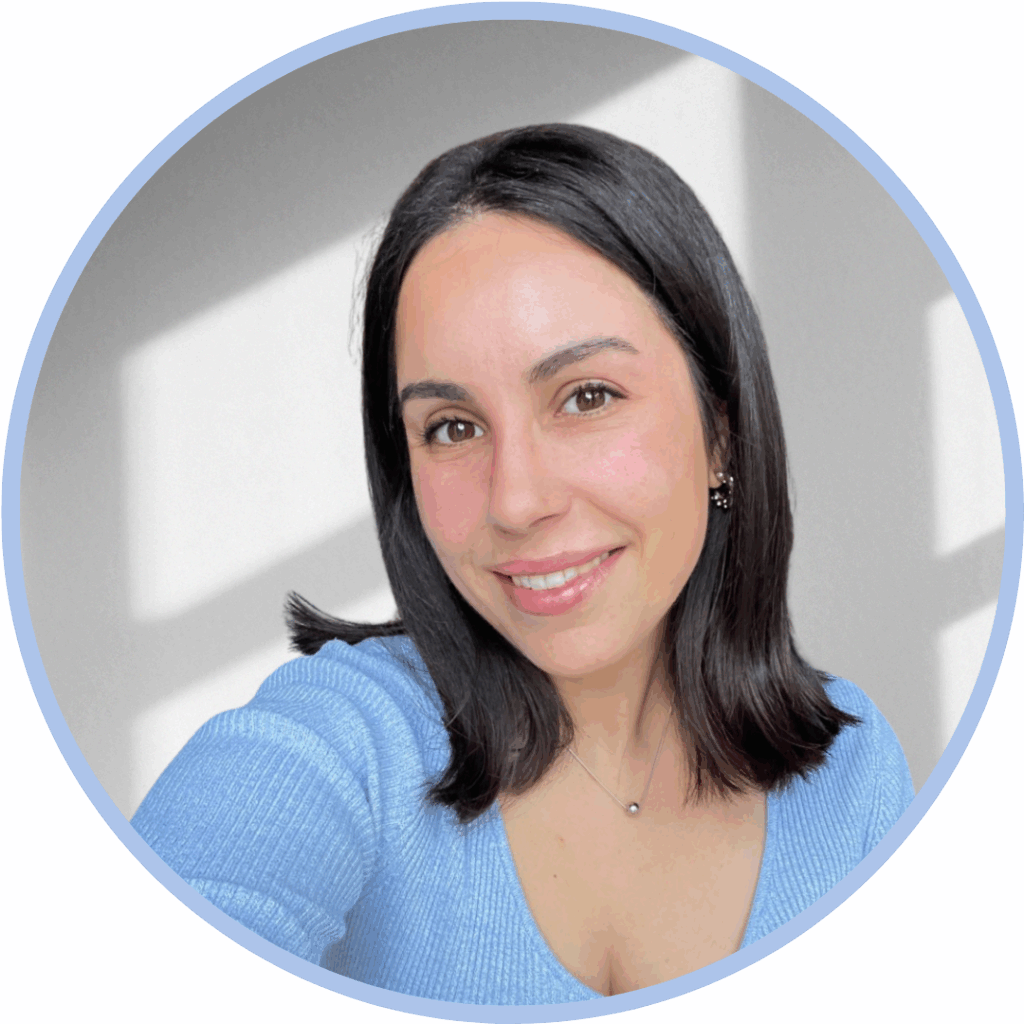 Headshot of a woman with shoulder length dark brown hair wearing a light blue top and smiling to camera