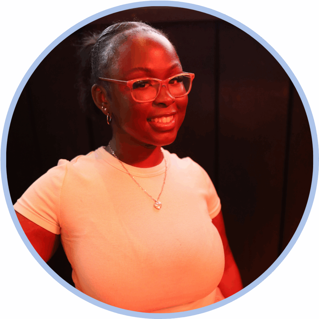 Headshot of a black woman wearing a white tshirt and glasses smiling to camera