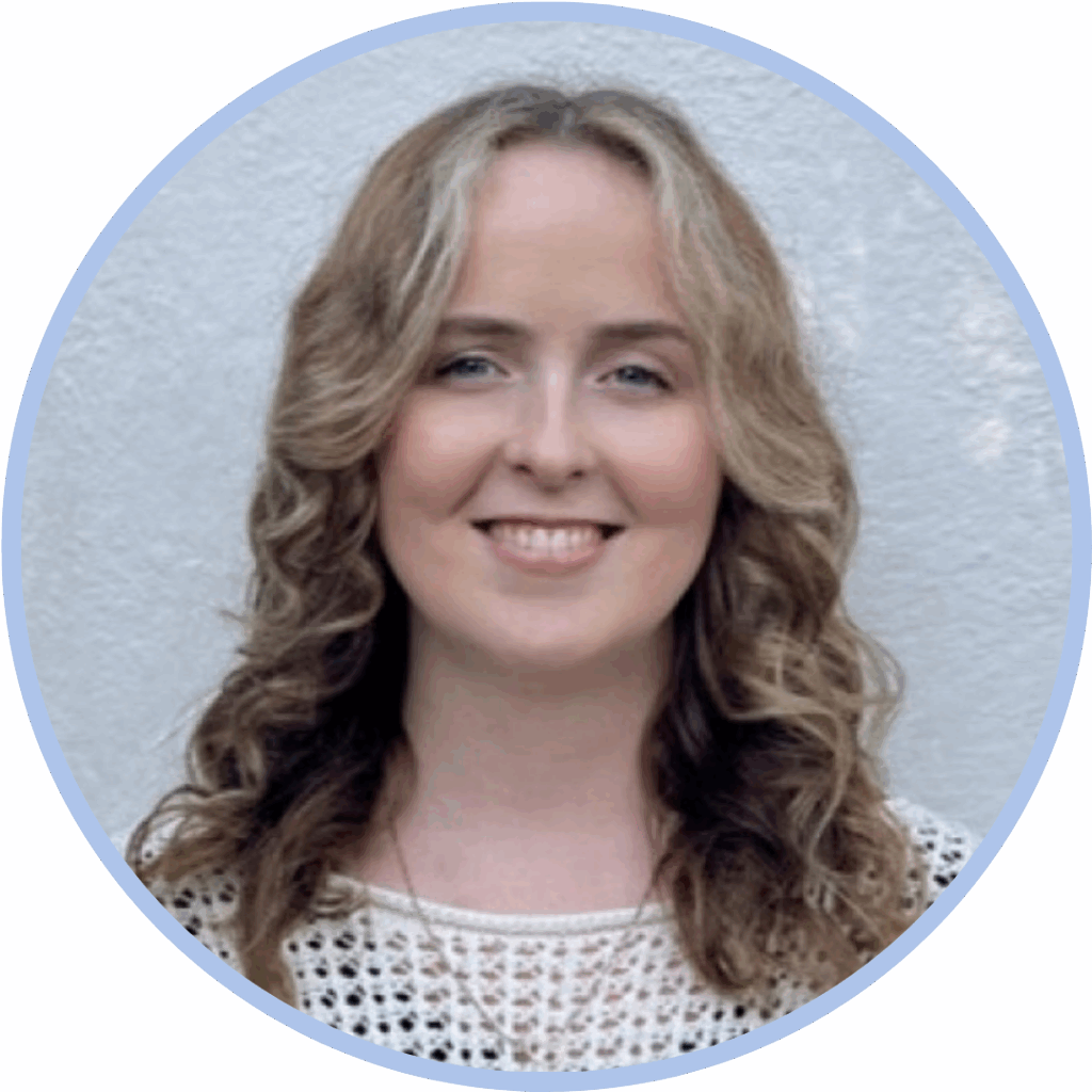 Headshot of a white woman with curled blonde/brown hair smiling to camera