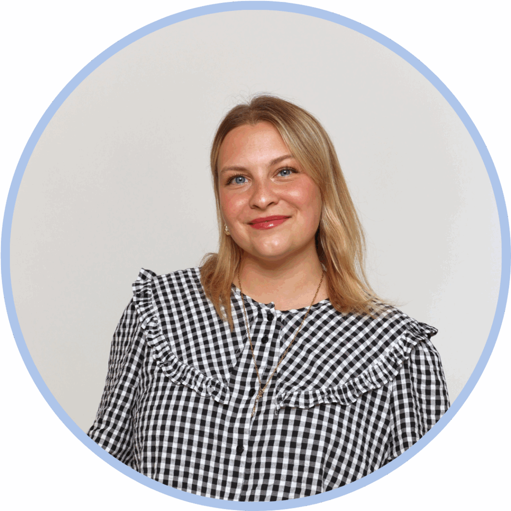 Headshot of a white woman with shoulder length blonde hair and wearing a black and white checked blouse smiling to camera